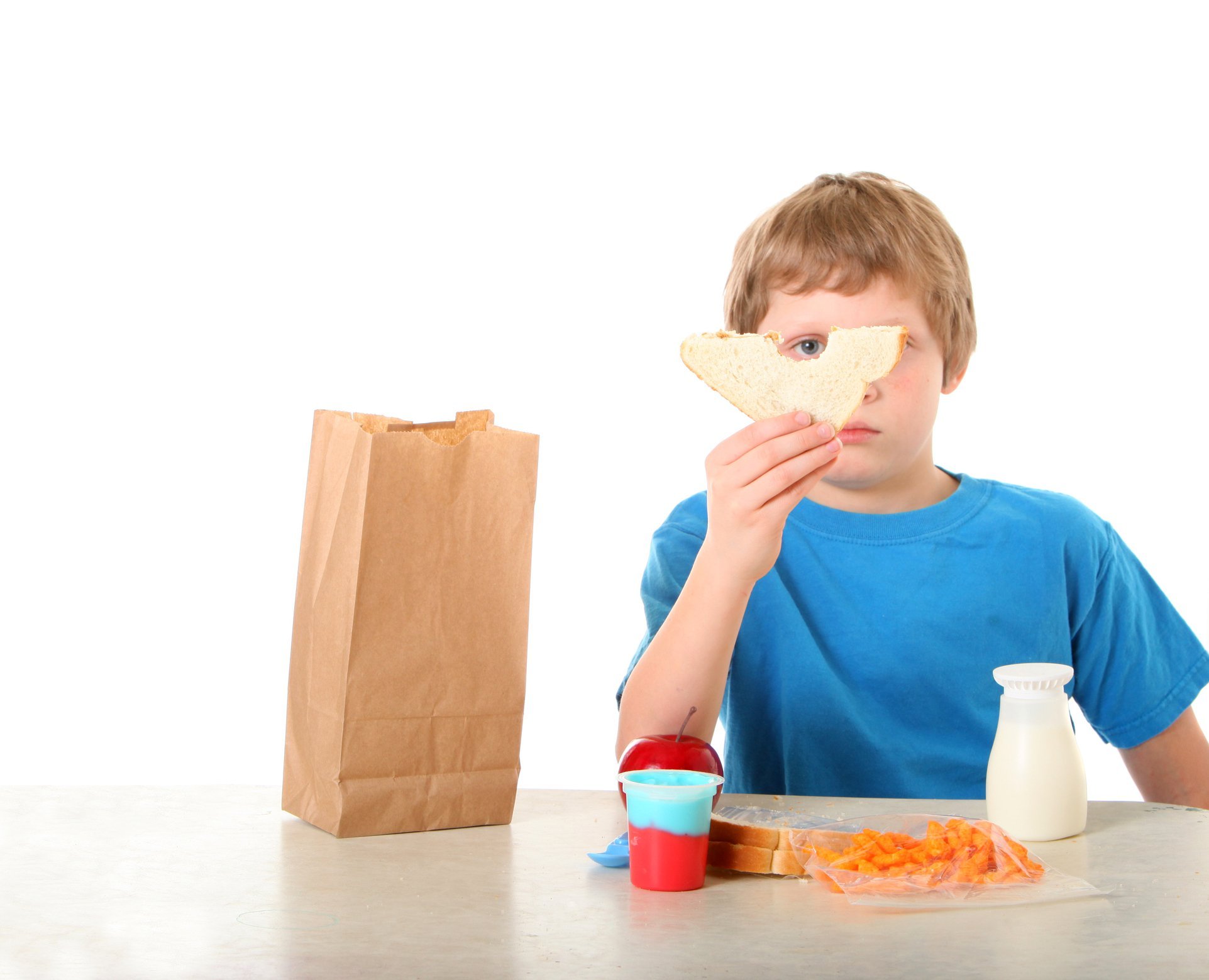Boy at table eating an unhealthy packed school lunch