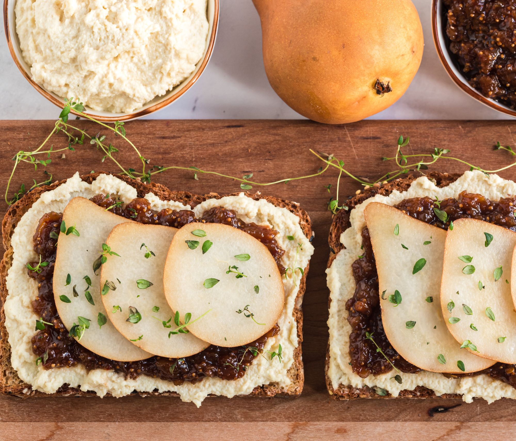 Almond Ricotta Pear Toast with Balsamic Fig Jam on a cutting board