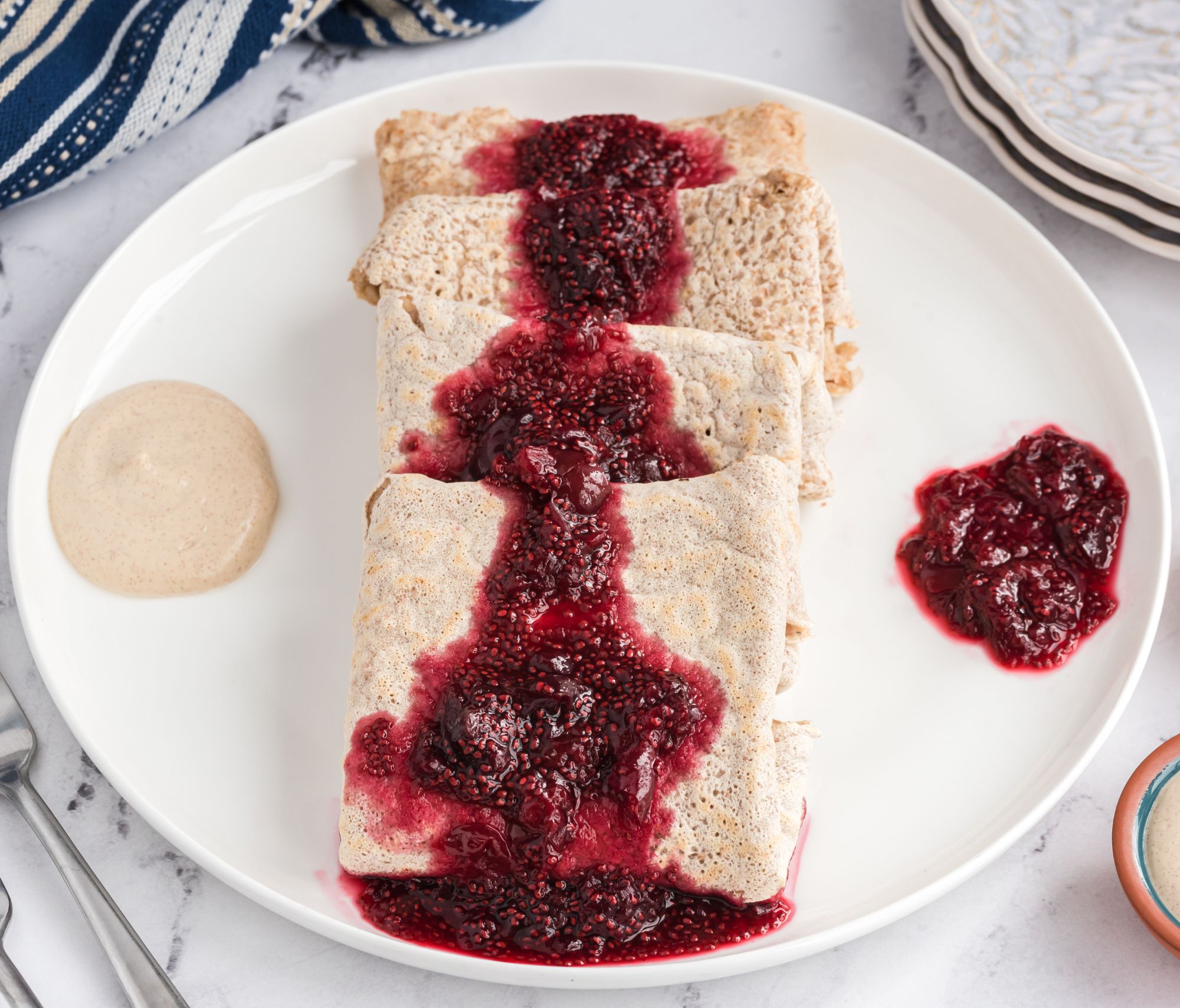 Cherry Vanilla Crepes with a jam topping cascading across the dessert