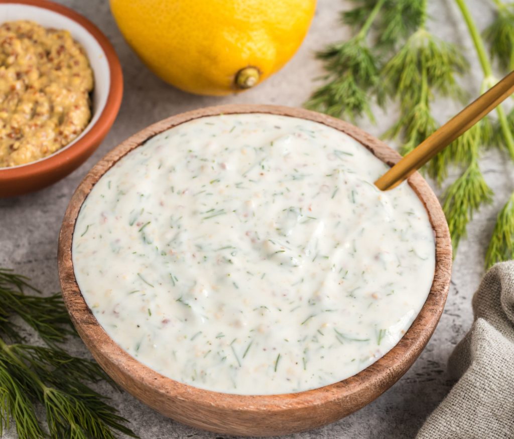 Creamy Mustard Dill Sauce on a table near a lemon and an additional dipping sauce