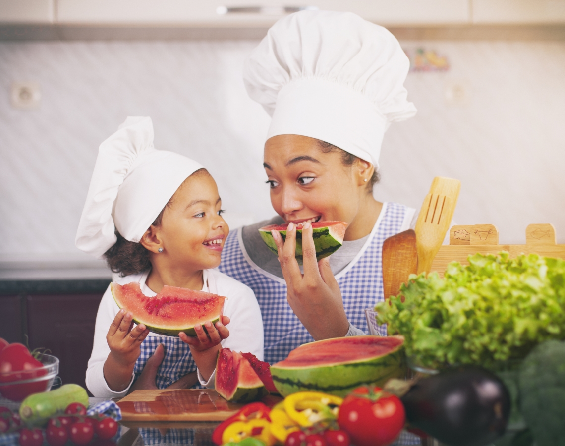 Mother and daughter eating watermelon in the kitchen