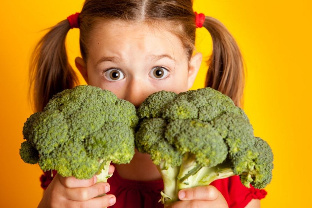 Little girl with two broccoli stalks