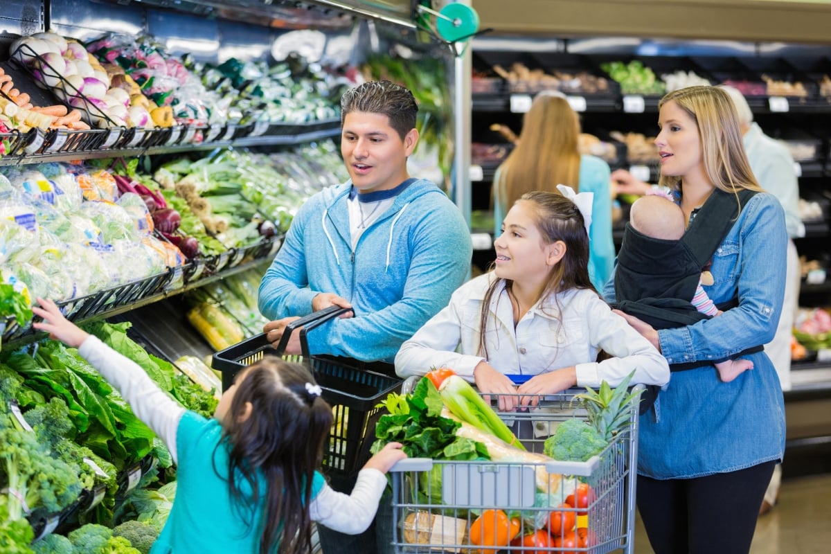 Large hispanic family shopping in the produce section of the grocery store.