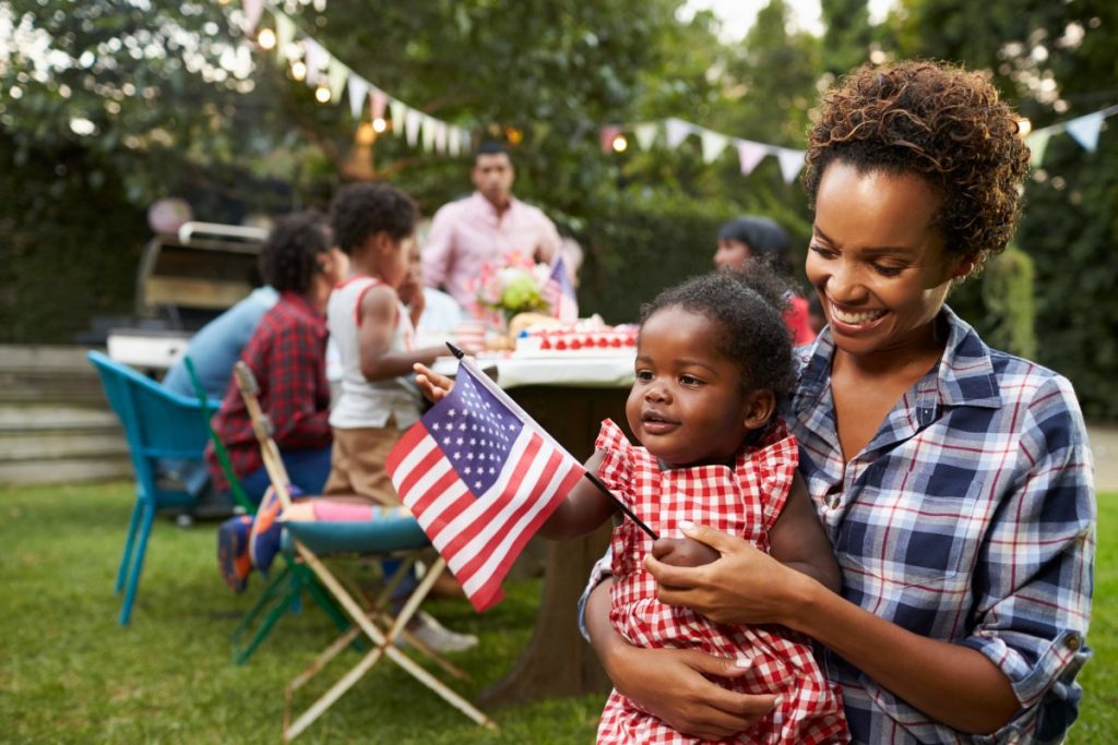 Woman holding her baby holding an American flag