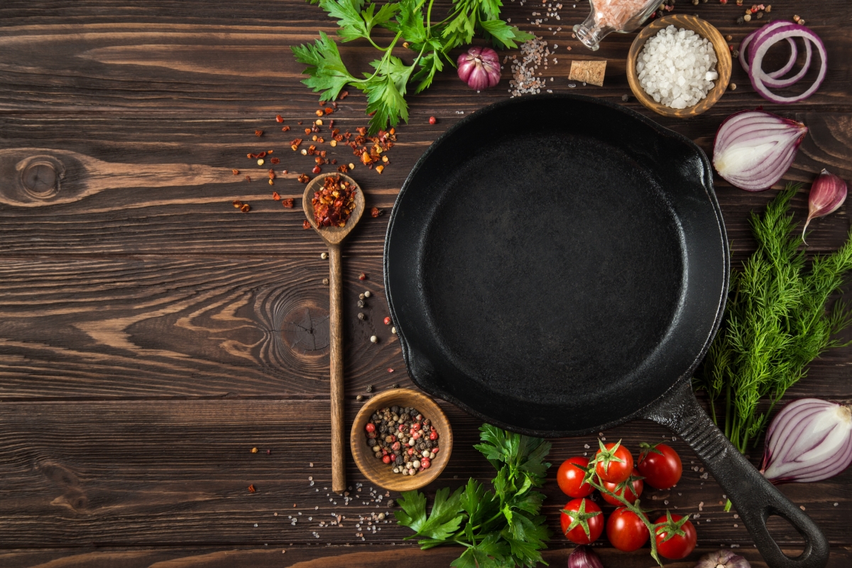 A cast iron pan surrounded by herbs