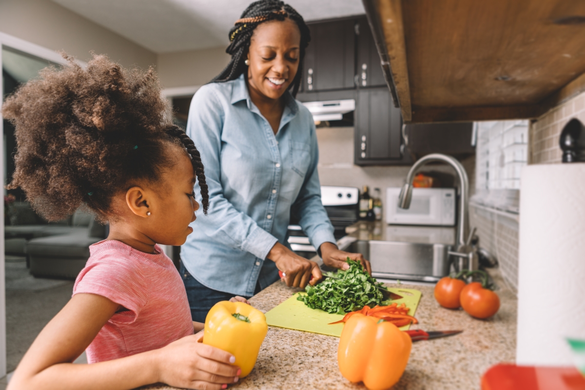 Healthy eating for kids: Mother chops vegetables in kitchen with daughter