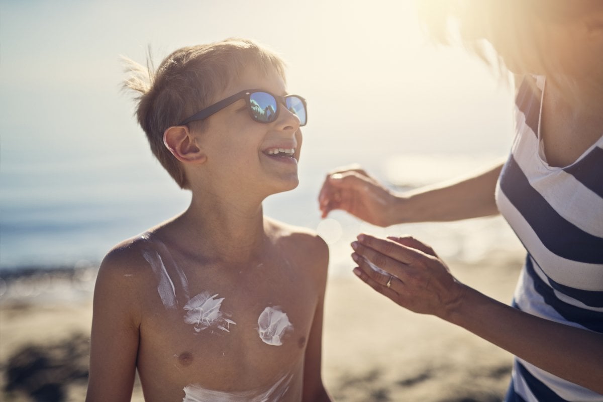 Mother putting sunscreen on her sun at the beach