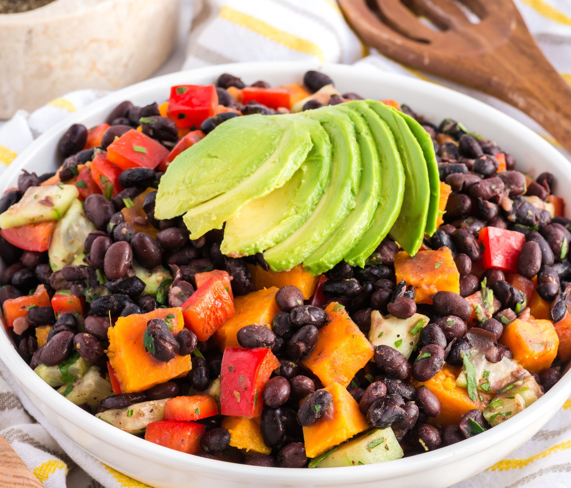 Smoky Sweet Potato Black Bean Salad in a white bowl near a wooden spoon