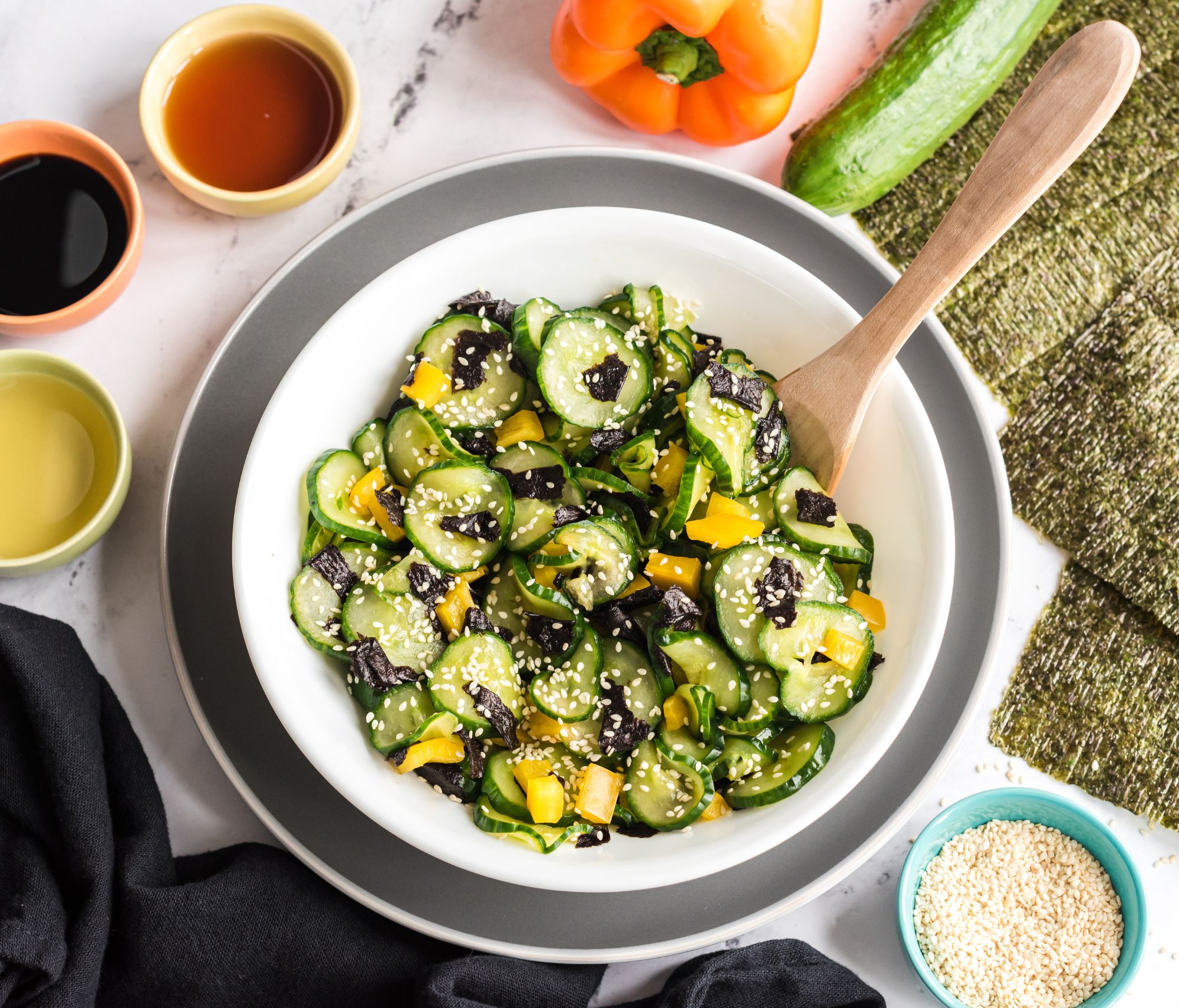 Sunomono Japanese Cucumber Salad within a bowl with dressings in nearby small bowls