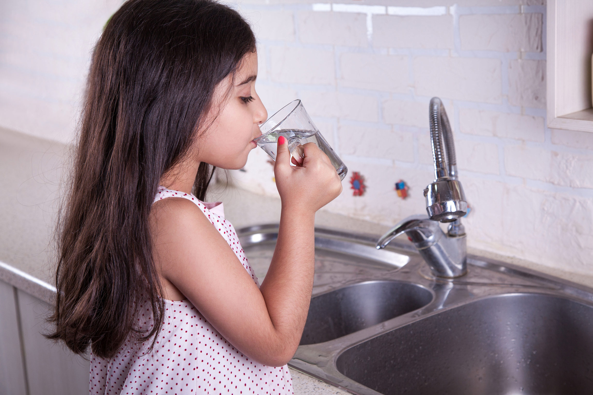 Little girl drinking a glass of tap water