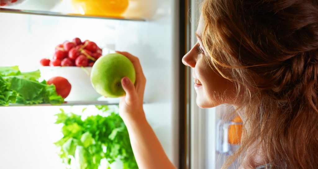 woman looking in fridge with healthy food