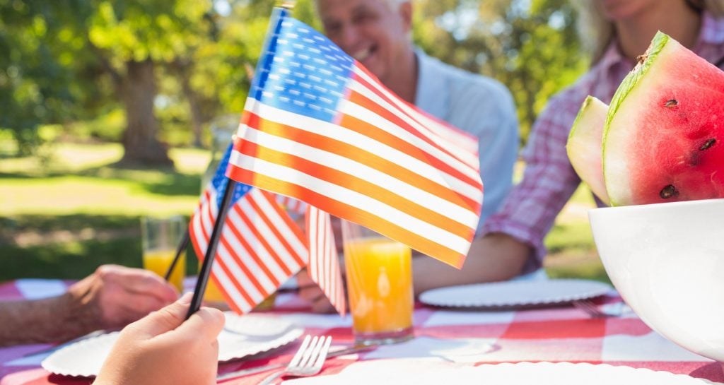 American flag being held by child at a picnic table