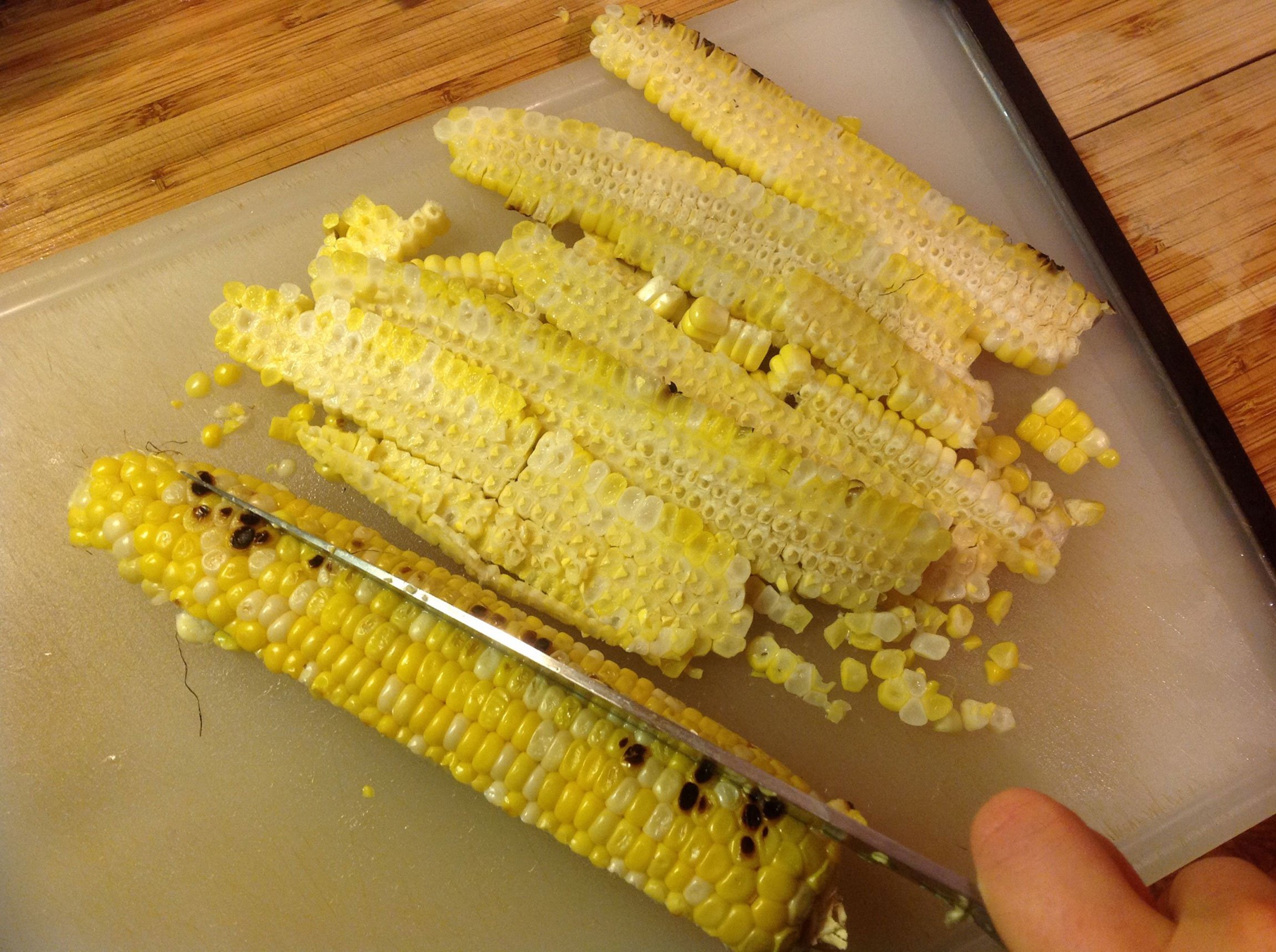 grilled corn being cut on cutting board