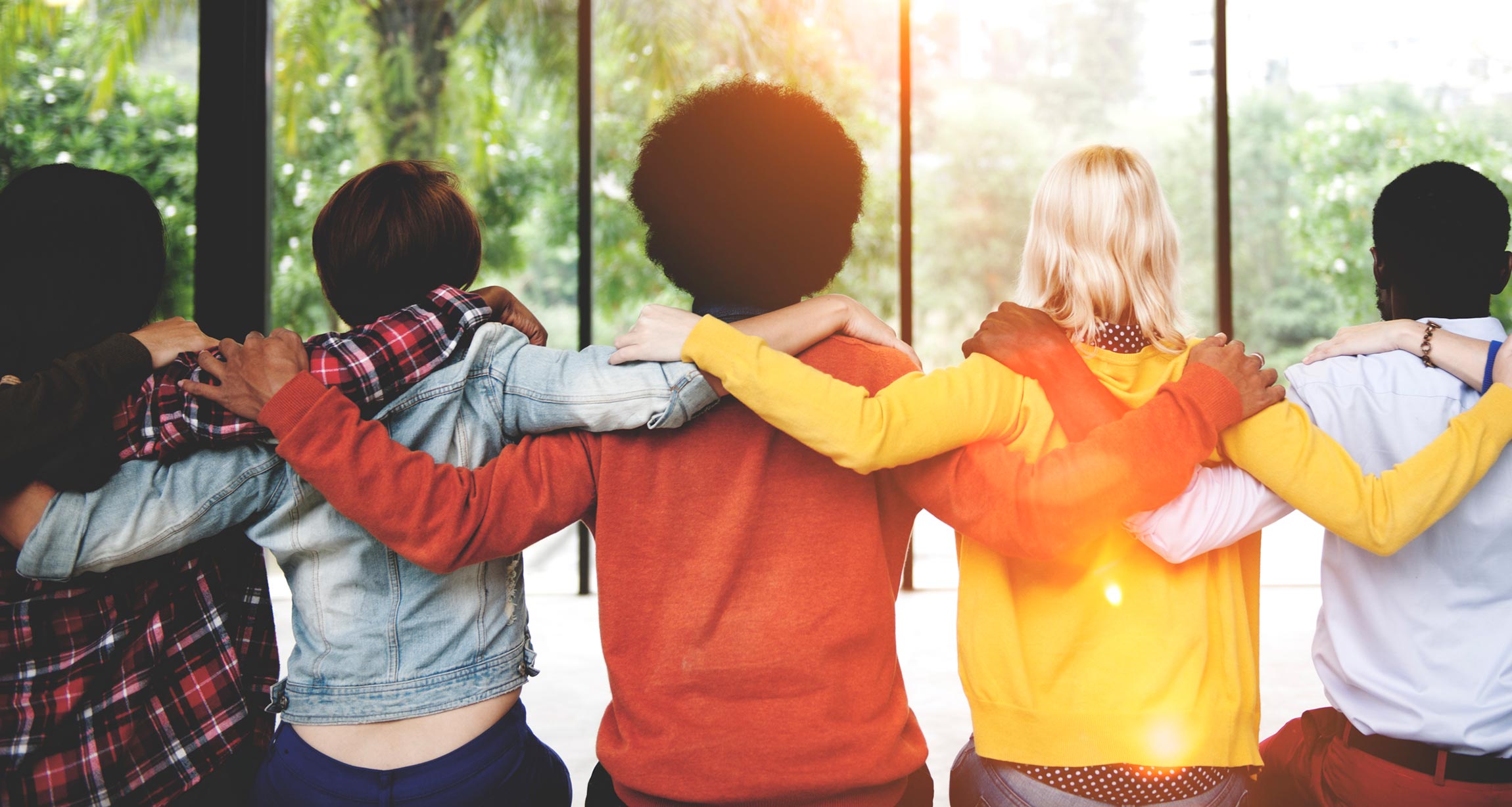 group of people sitting in line with arms on each others' shoulders