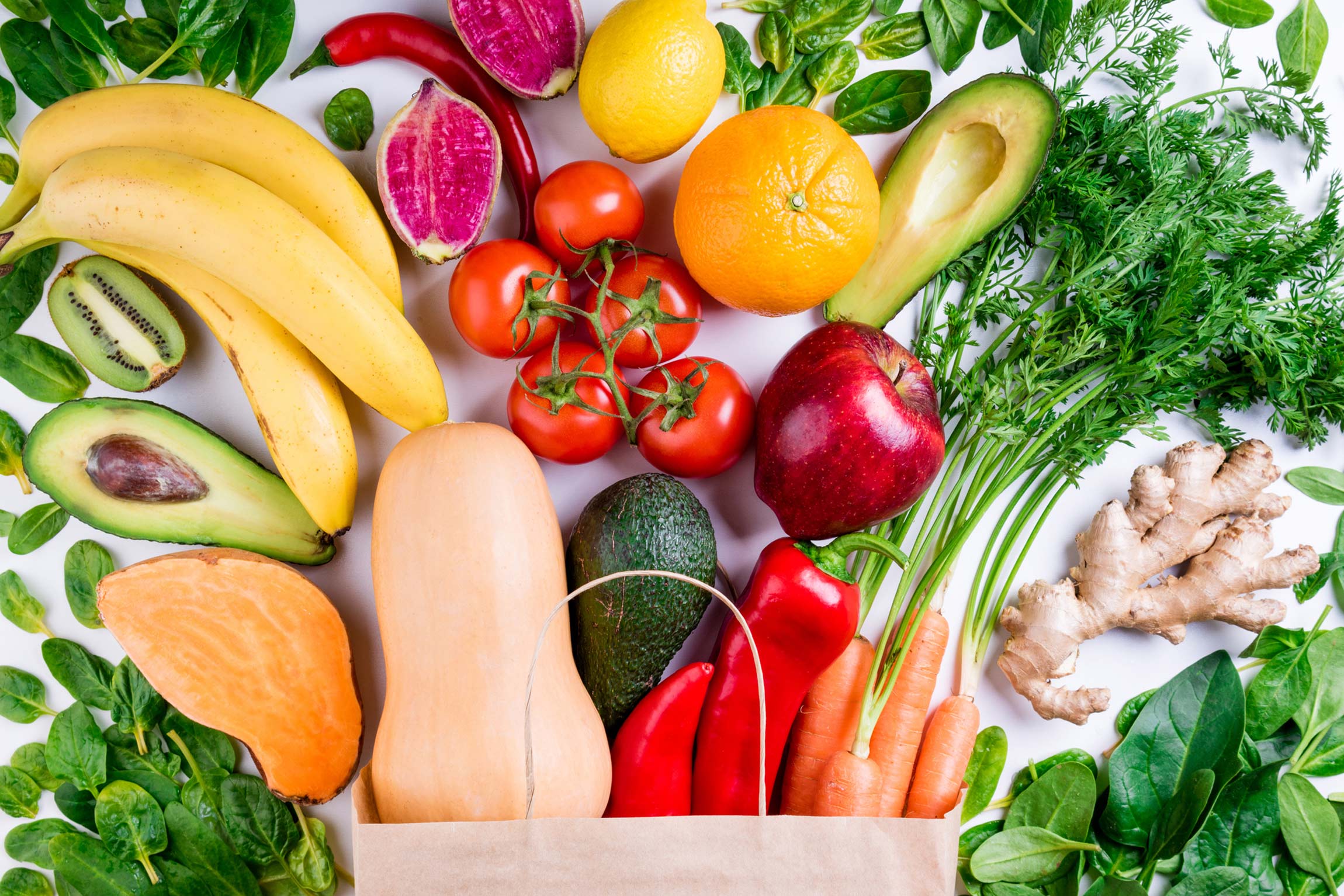 A paper bag bursting with fresh fruits and vegetables