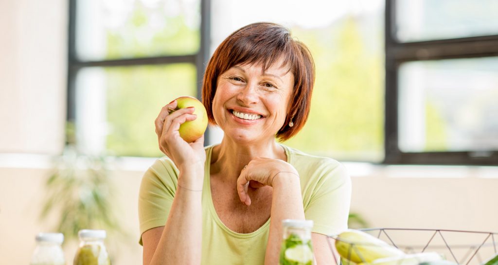 Woman holding an apple and smiling