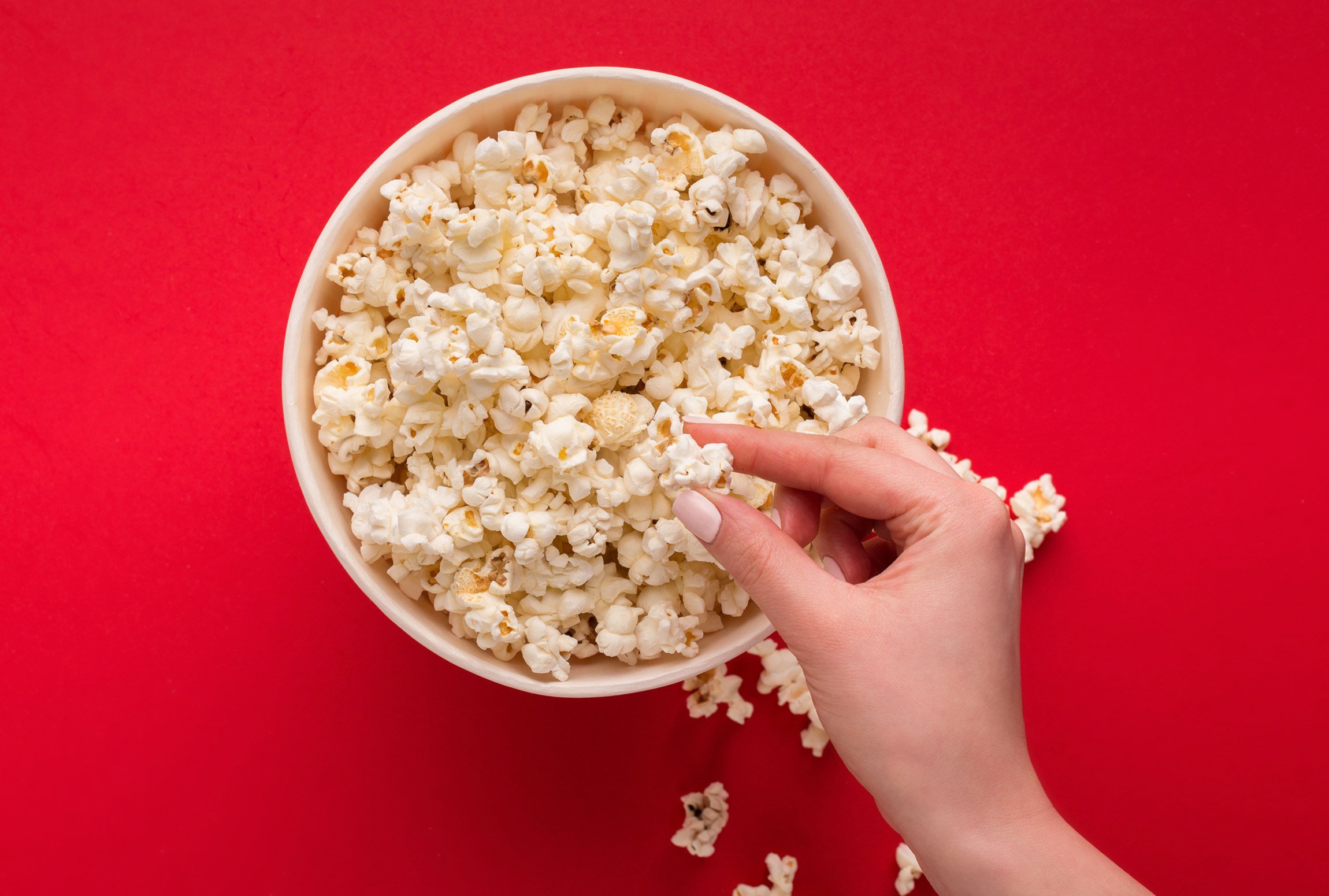 A hand taking popcorn out of a bowl