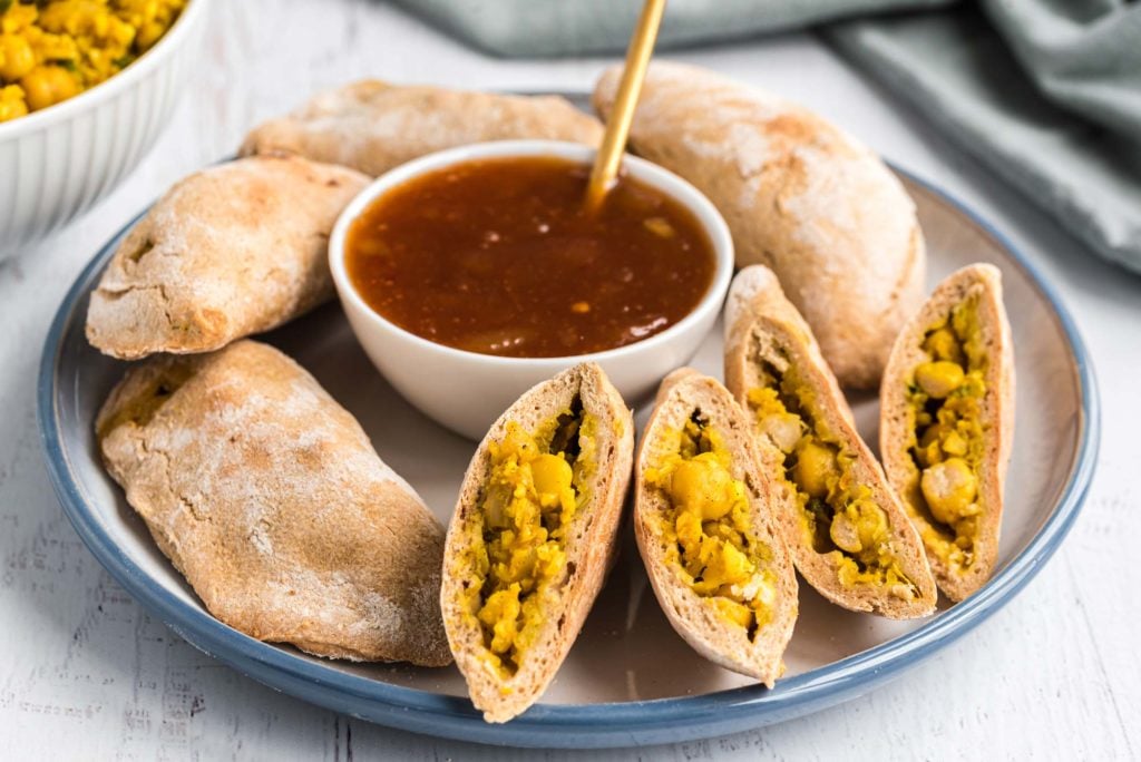 cauliflower and chickpea samosas on serving plate with sauce