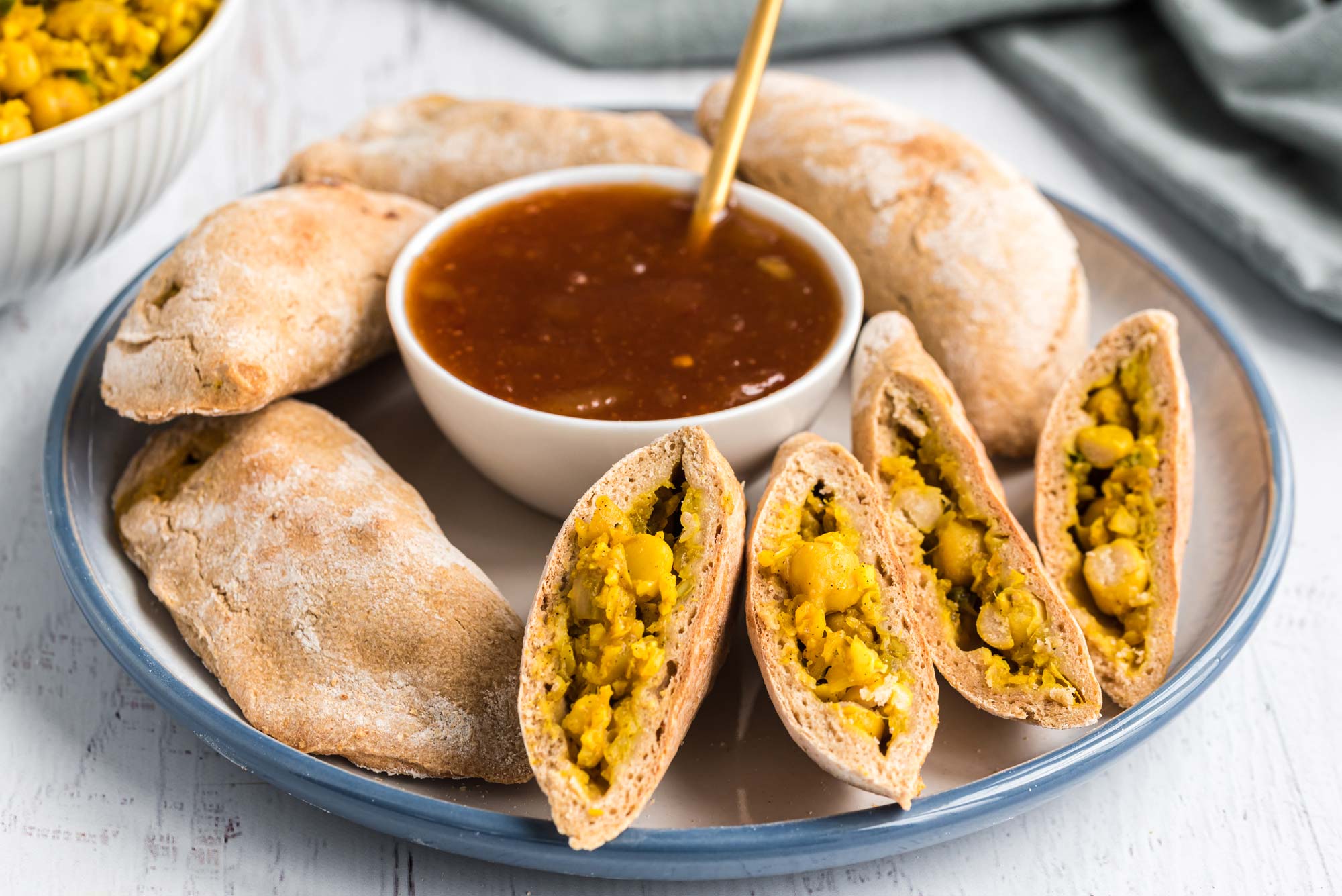 cauliflower and chickpea samosas on serving plate with sauce