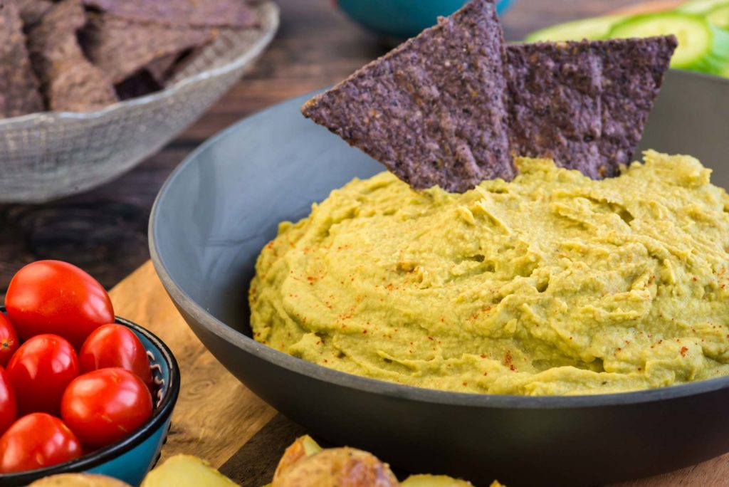 green pea hummus in bowl with chips