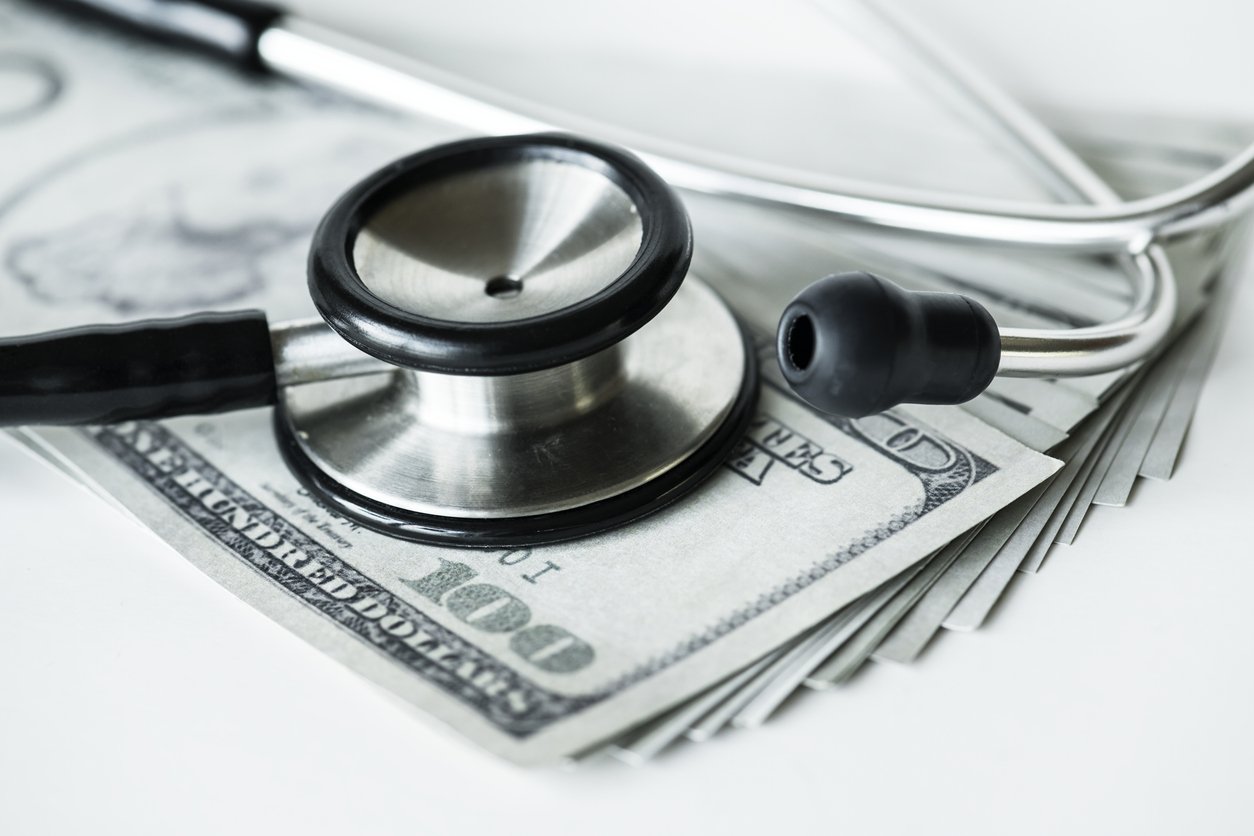 closeup of cash and a stethoscope healthcare and expenses concept