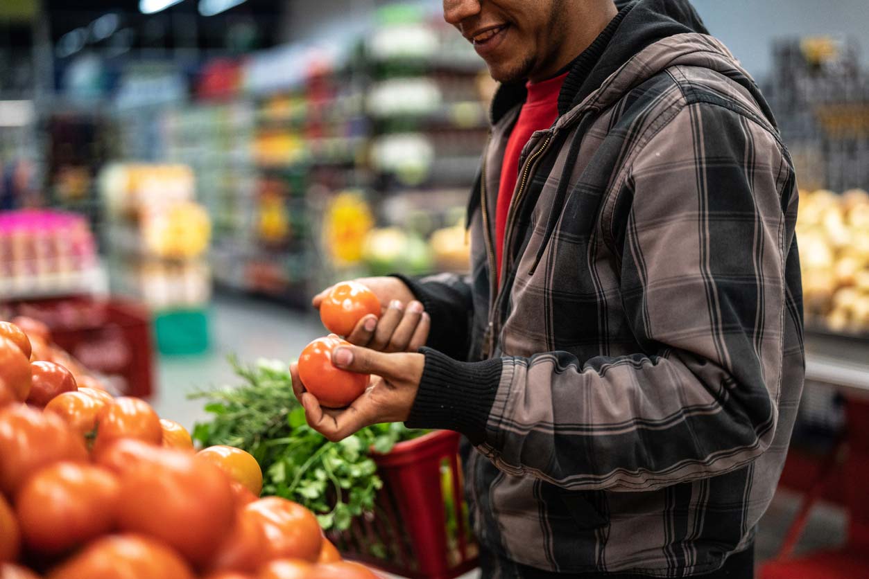 man choosing tomatoes in grocery store