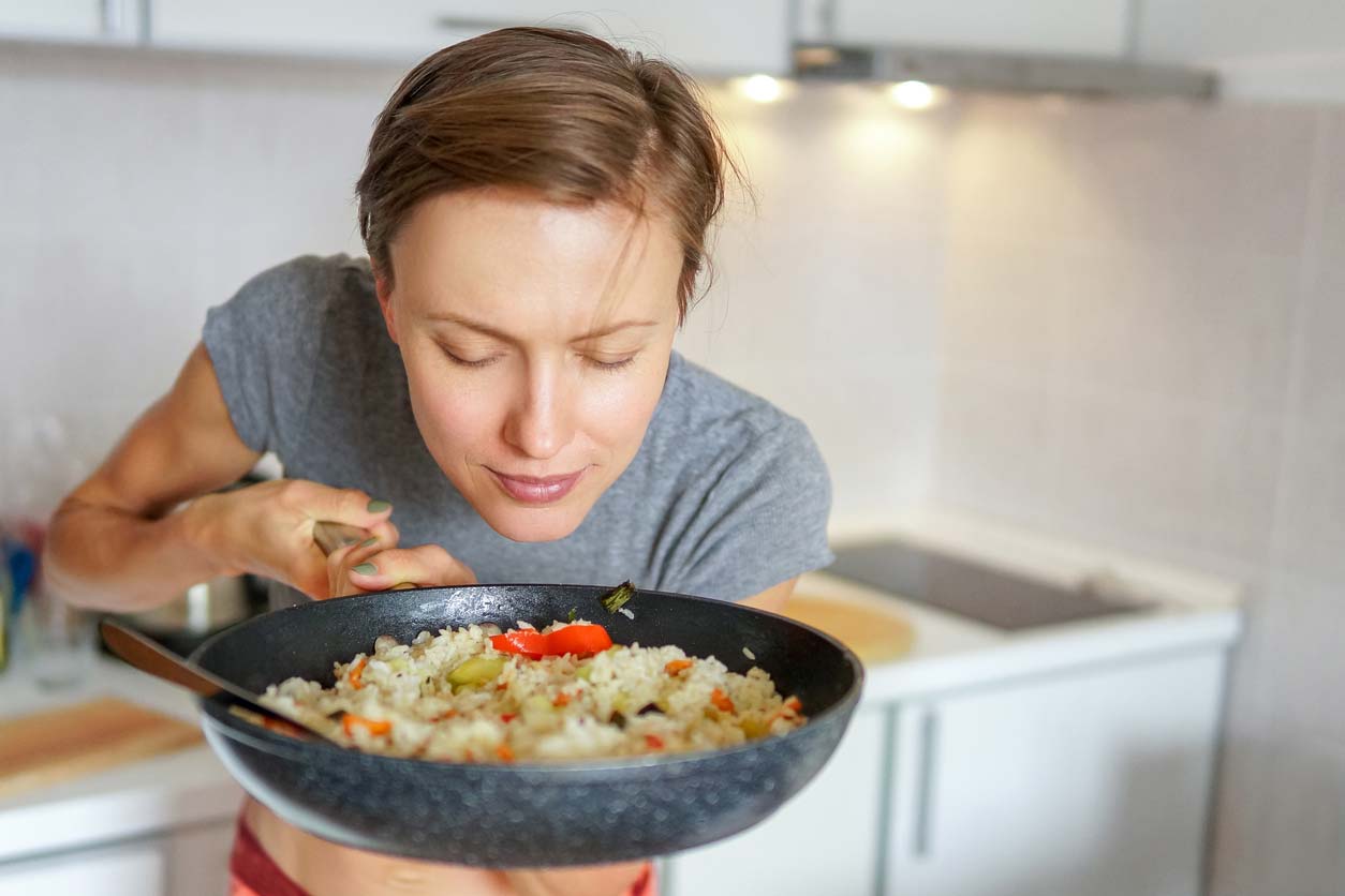 woman holding pan with rice and vegetables