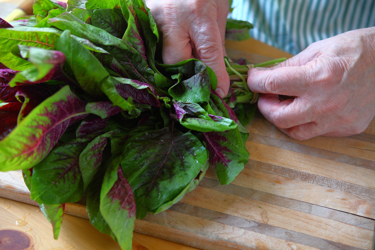 Male cook removes rubber band from bunch of amaranth greens 