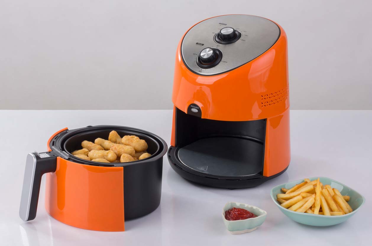 bright orange air fryer on counter with food