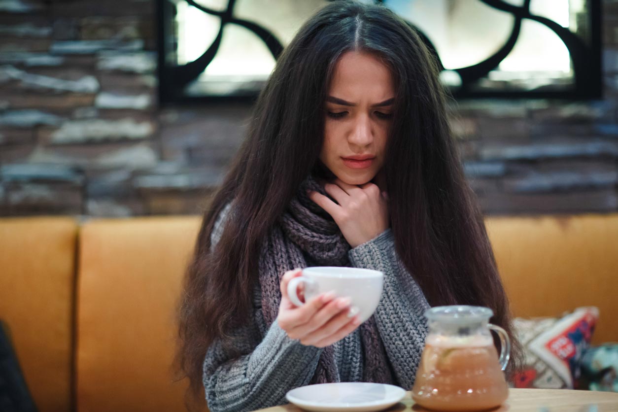 woman appears sick and holding mug