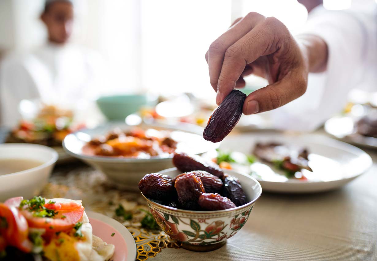 hand picking a date out of a bowl on a set table