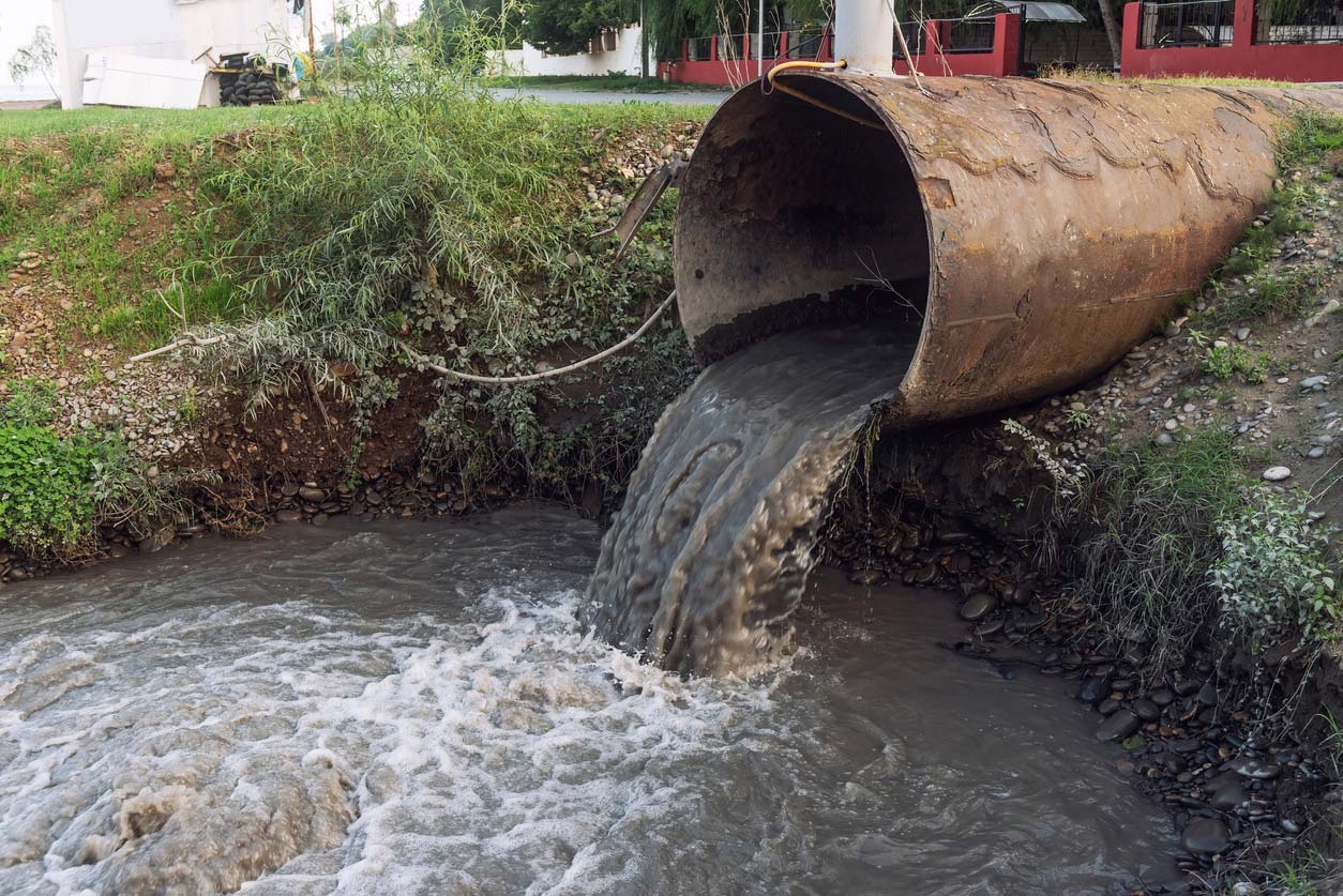 dirty sewage water pouring into drainage ditch