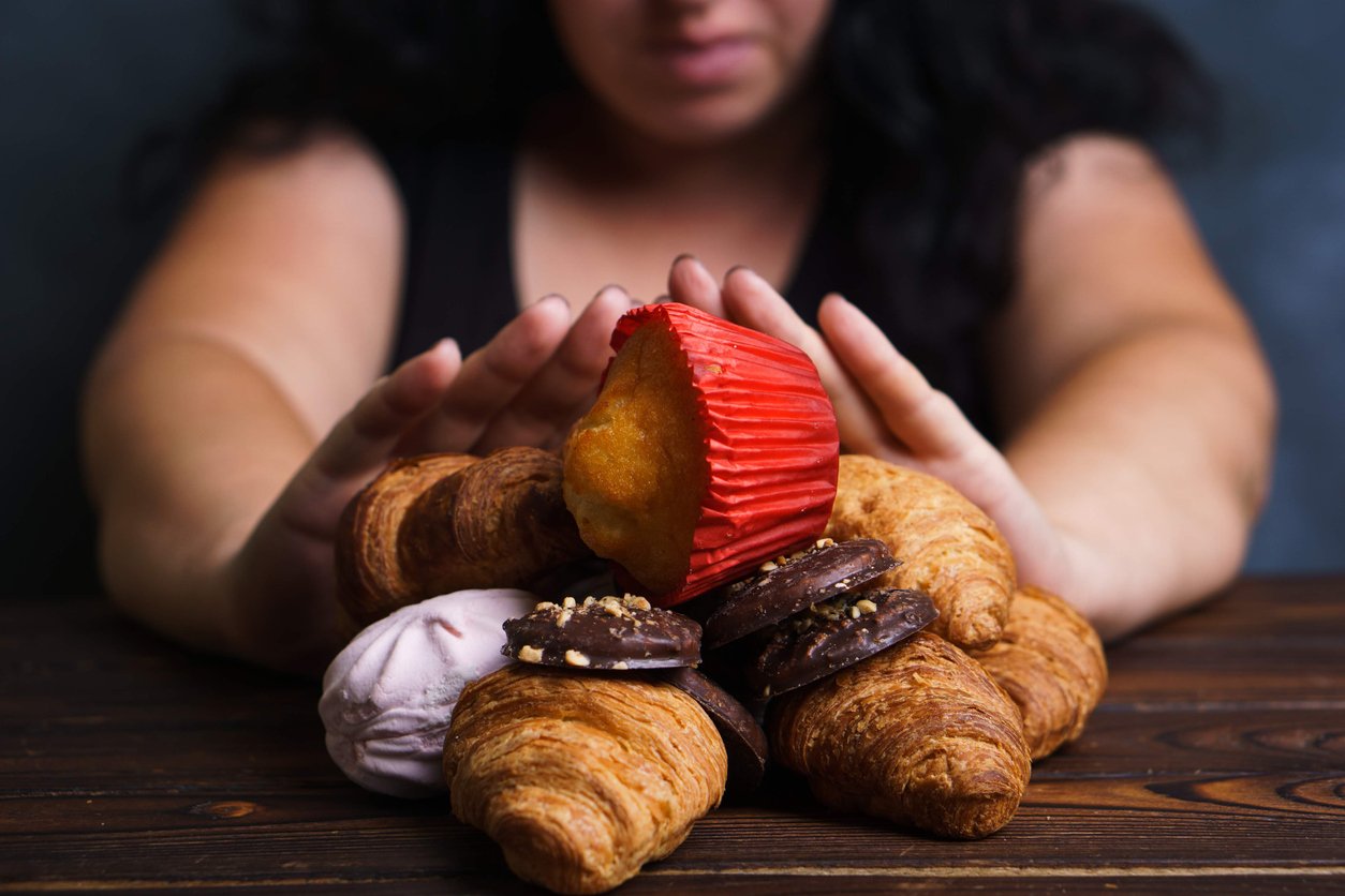 Woman pushing away processed foods high in fat and sugar