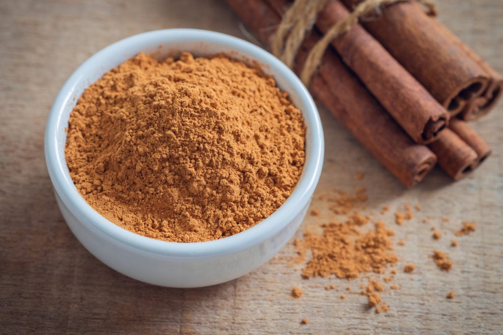 Cinnamon powder and cinnamon sticks on wooden table