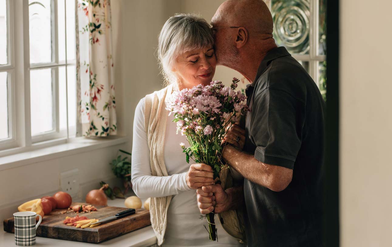 senior couple at home exchanging flower gift