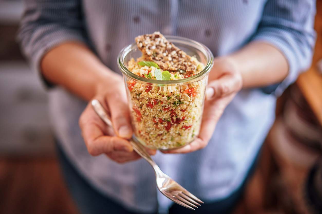 quinoa sald in jar being held by woman