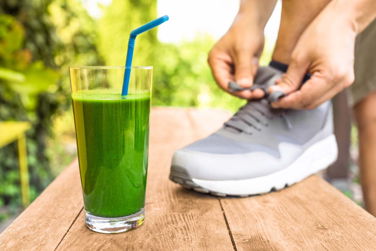 green smoothie next to someone tying shoe