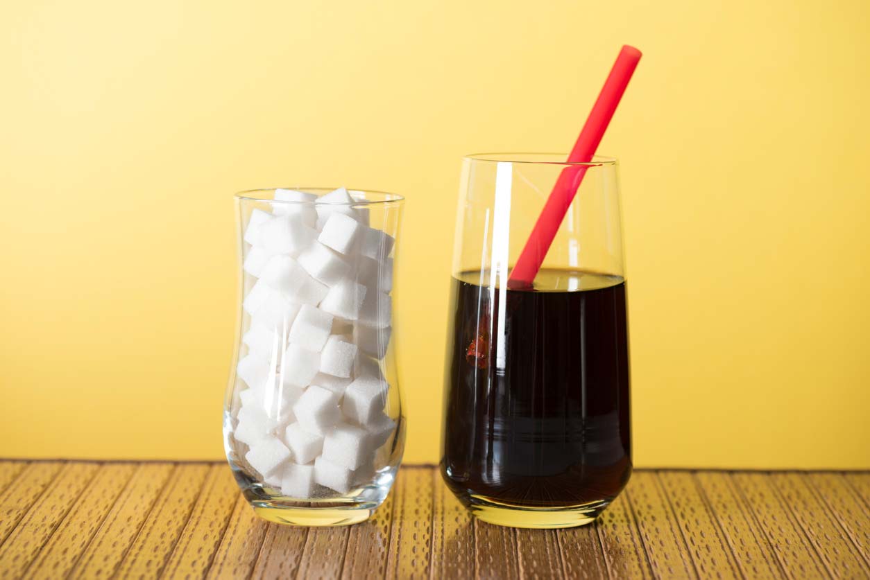 soda next to glass of sugar cubes