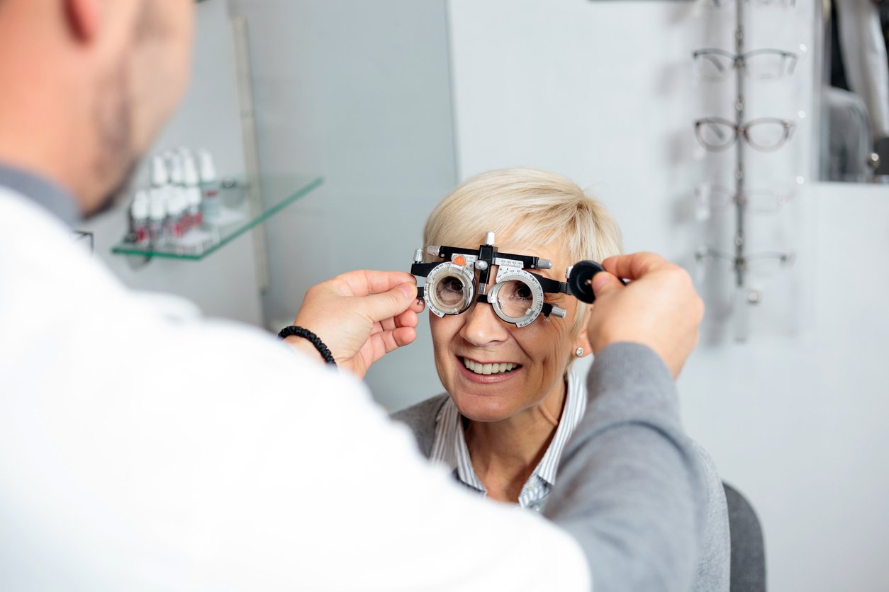 Smiling mature woman having eyesight exam and diopter measurement at the ophthalmology clinic. Healthcare and medicine concept