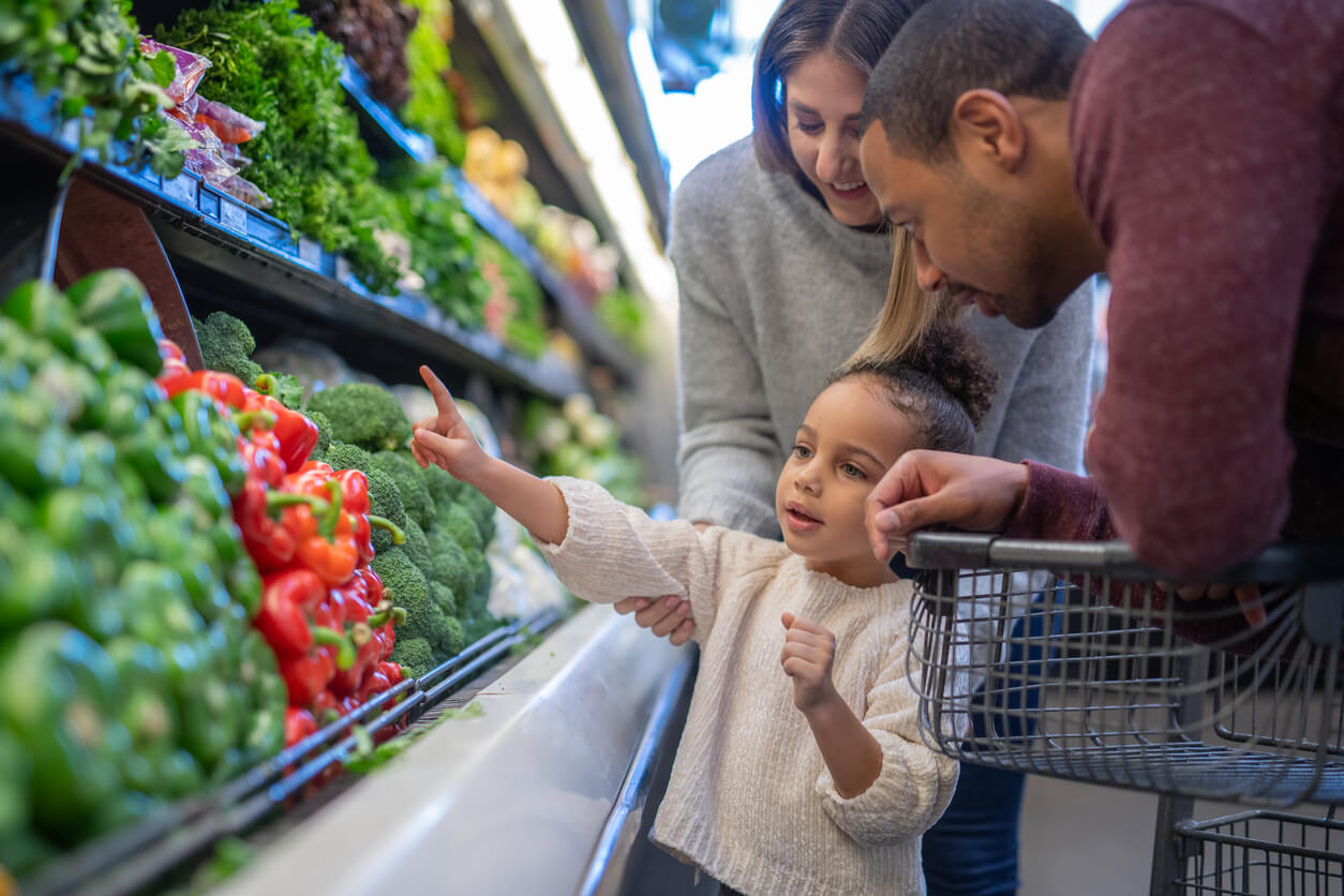 mixed race couple grocery shopping with their preschool age daughter