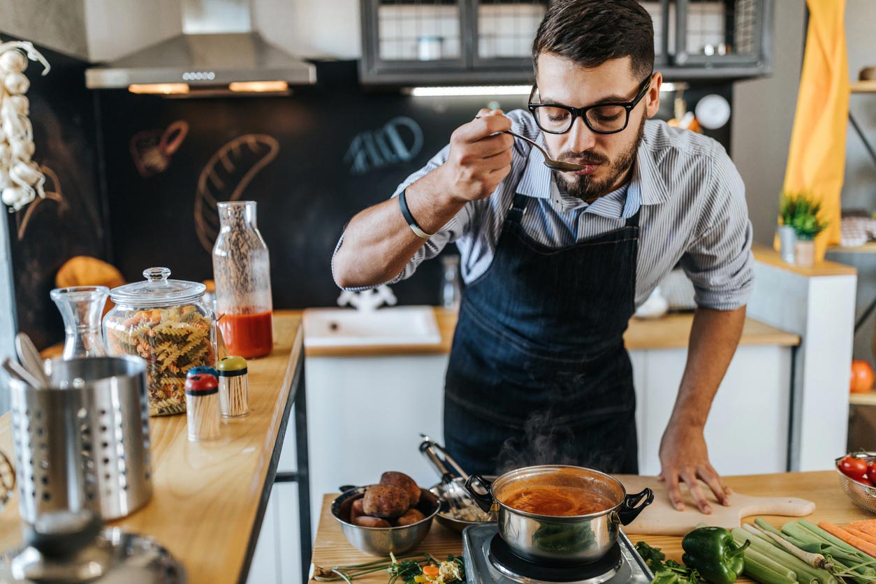 man tasting food while cooking