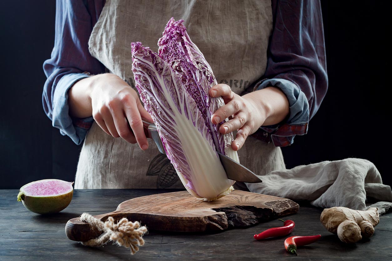 woman cutting purple cabbage