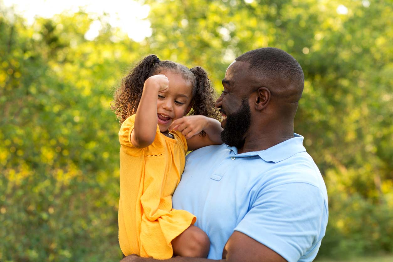 Dad holding daughter doing strong arm