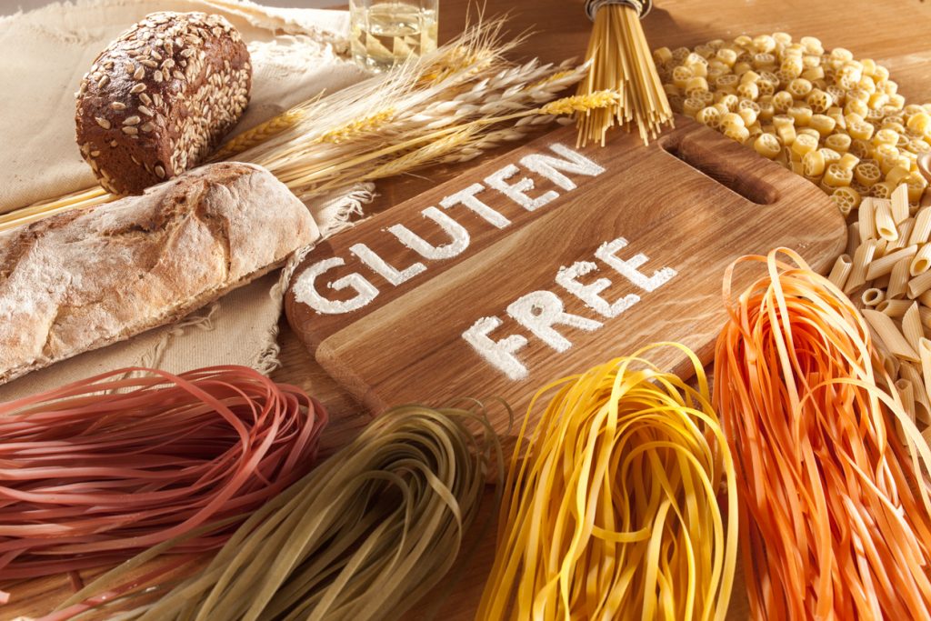 Gluten free food. Various pasta, bread and snacks on wooden background from top view.