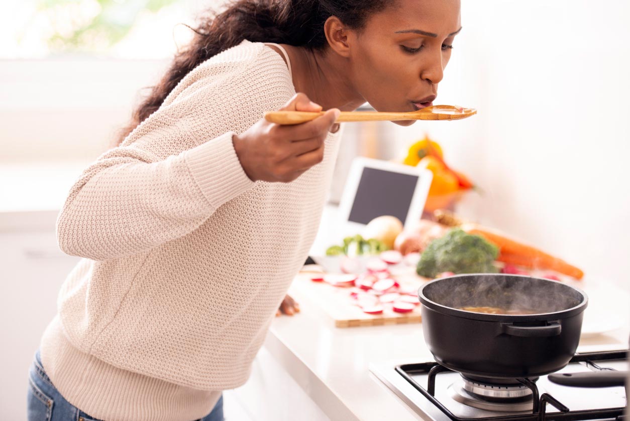 女人用木勺品嚐湯