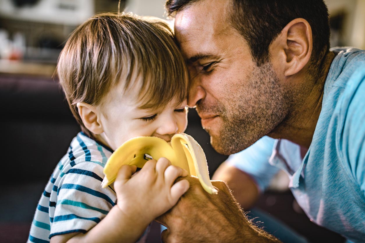 father feeding boy with banana