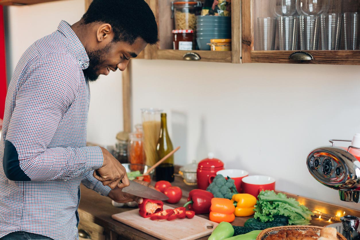 man cutting bell pepper in kitchen