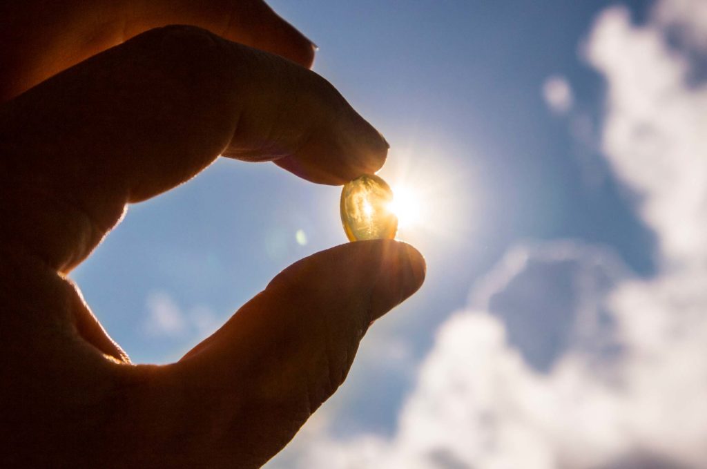 Vitamin D capsule being held up to the sun
