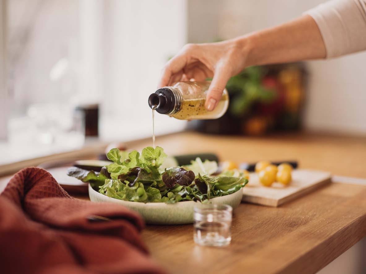 pouring vinegar dressing over salad