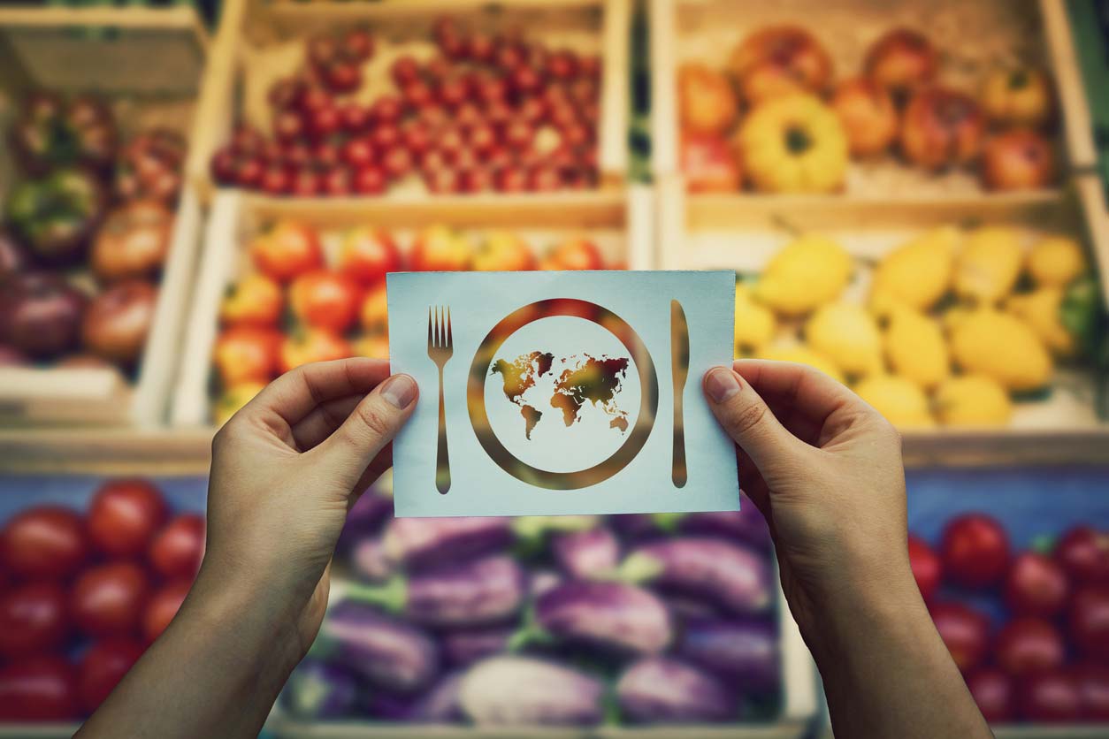 person holding cutout paper of globe with fork and knife